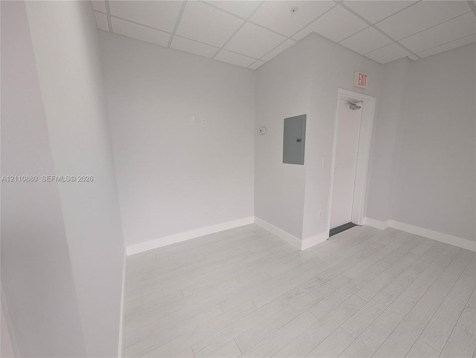 Interior space featuring neutral wall paint, wood-finish flooring, and drop ceiling tiles