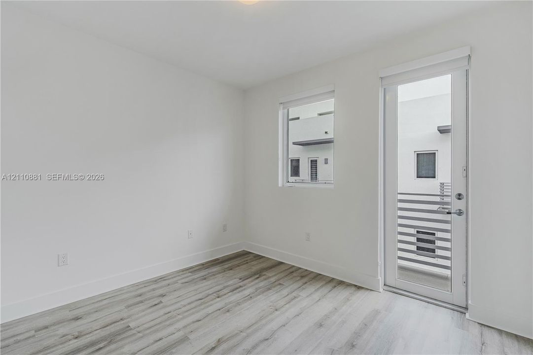 Neutral-toned interior featuring wood-finish flooring, a full-lite glass door, and a single-pane window
