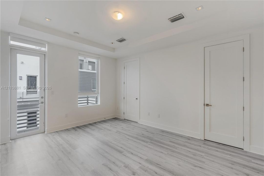 Interior space featuring wood-finish flooring, recessed ceiling lighting, a tray ceiling, and a full-light glass door