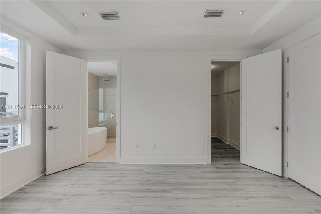 Tray ceiling with recessed lighting, wood-finish flooring, and shaker-style interior doors