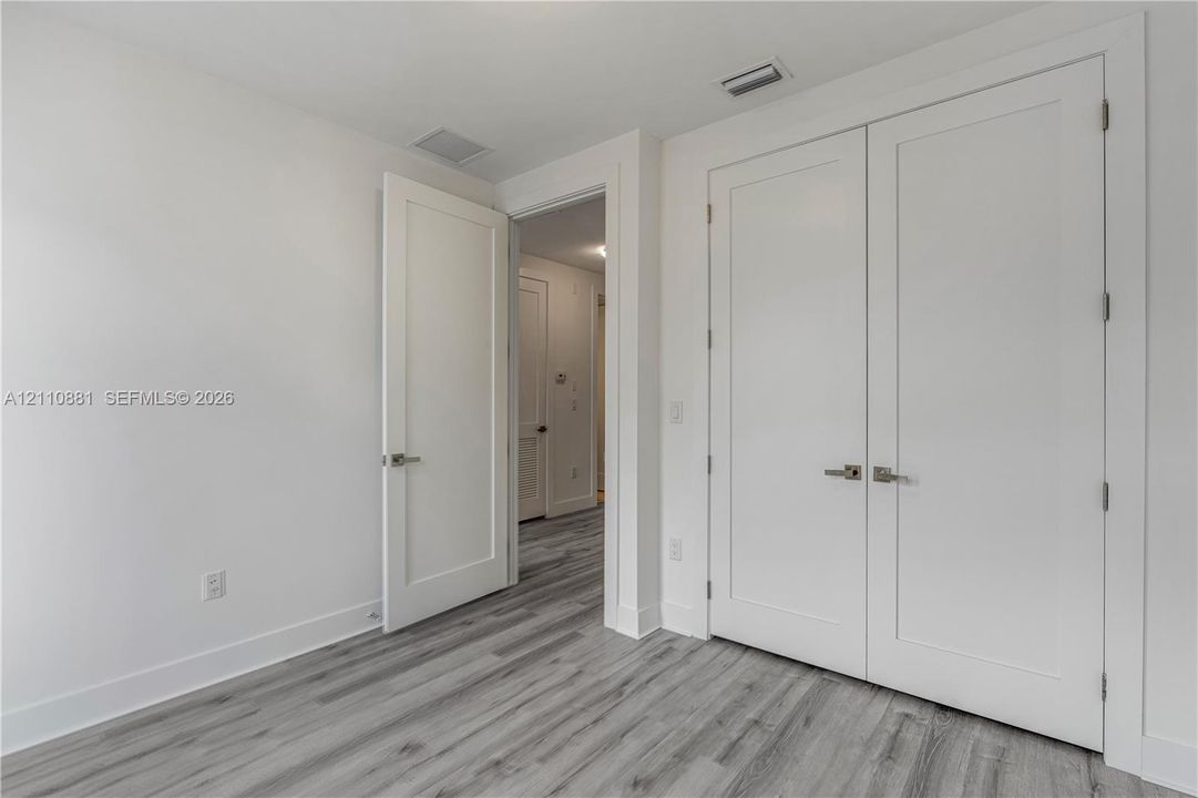 Interior space featuring wood-finish flooring, white shaker-style doors, and satin nickel hardware