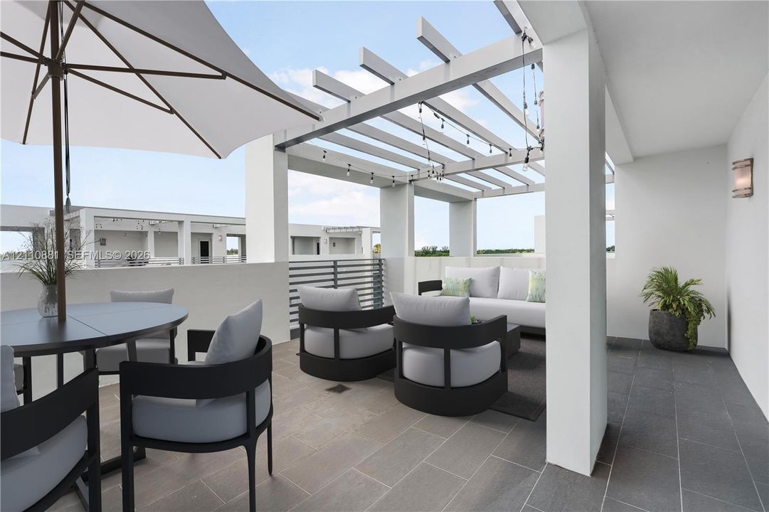 Covered terrace featuring large-format tile flooring, a pergola structure, integrated wall-mounted lighting, and metal railing