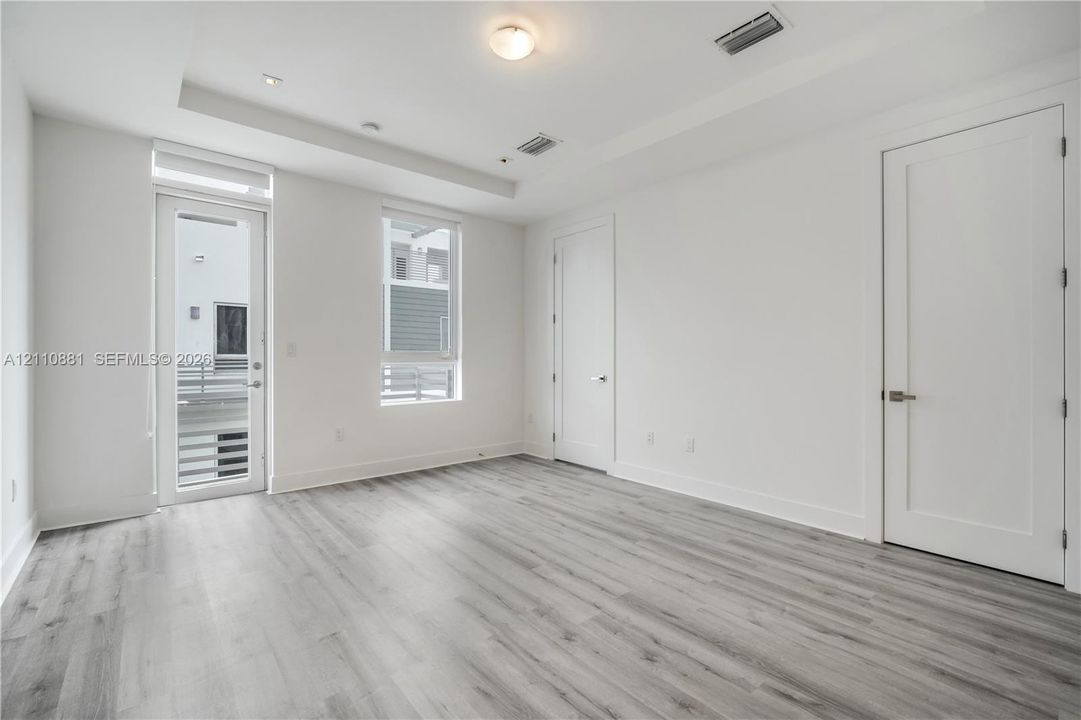 Interior space featuring wood-finish flooring, tray ceiling, full-light door, and solid-core interior doors