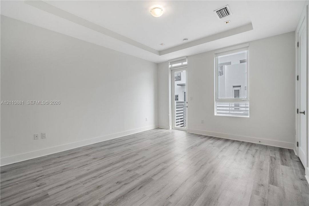 Interior space featuring wood-finish flooring, tray ceiling, recessed lighting, and a glass-paneled door