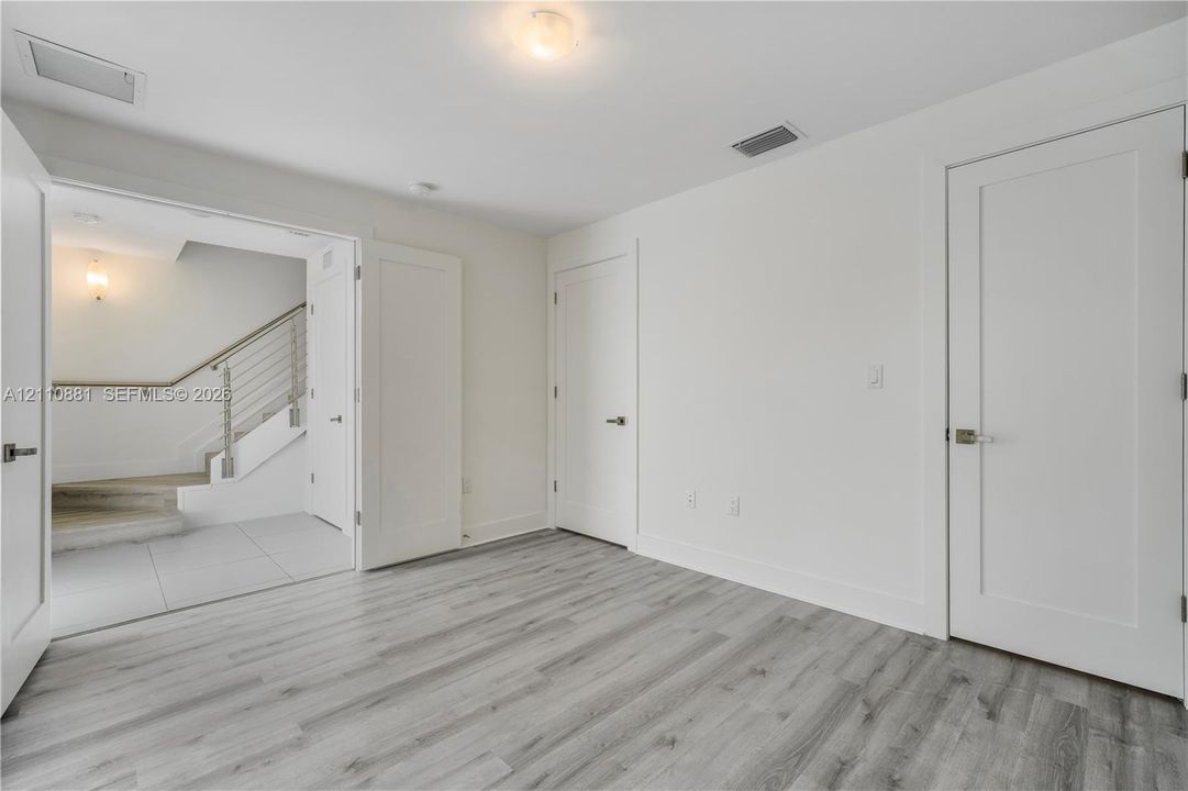 Interior space featuring wood-finish flooring, white shaker-style interior doors, and neutral wall tones