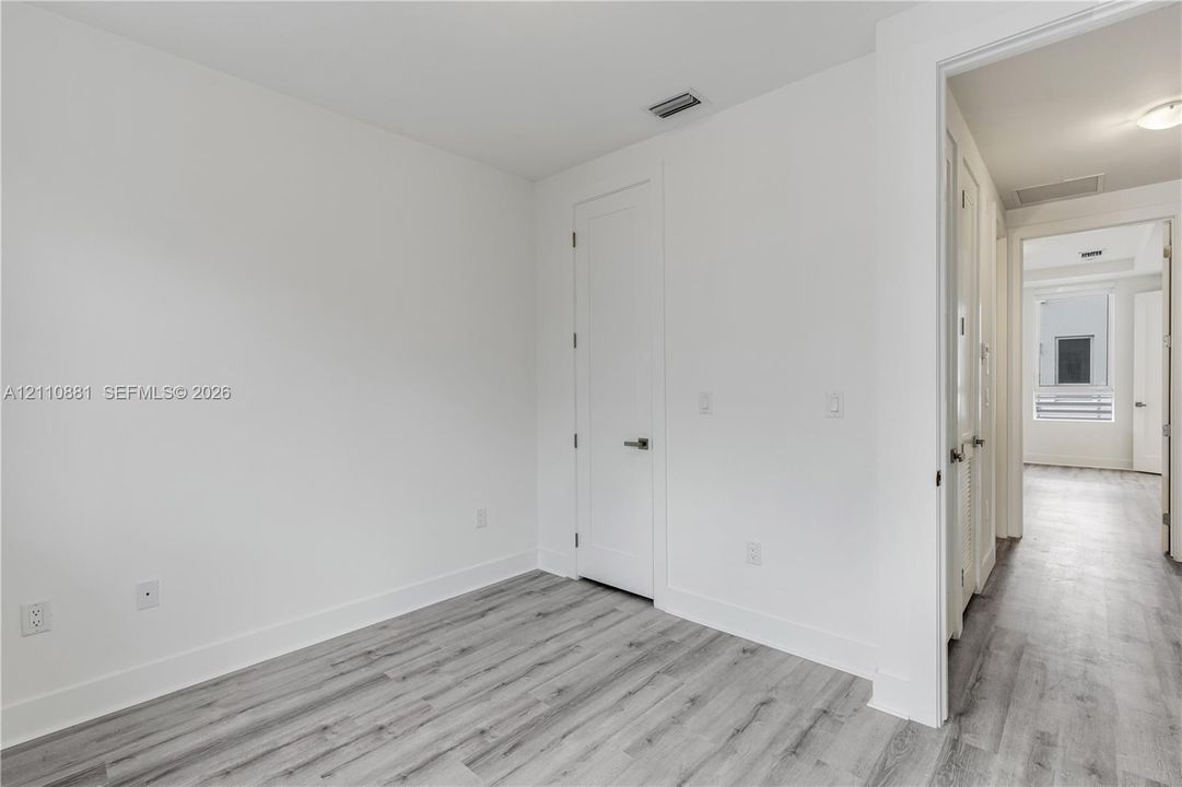 Neutral interior space featuring wood-finish flooring, solid-core doors, and crisp white walls