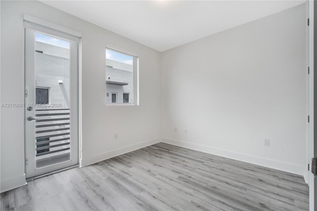 Neutral-toned interior featuring wood-finish flooring, a full-lite glass door, and a rectangular window