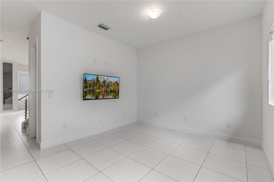 Neutral-toned interior space featuring large-format tile flooring, crisp white walls, and a recessed ceiling light fixture