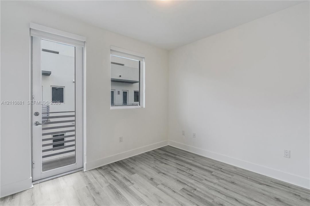 Neutral interior featuring wood-finish flooring, a full-lite glass entry door, and large rectangular windows
