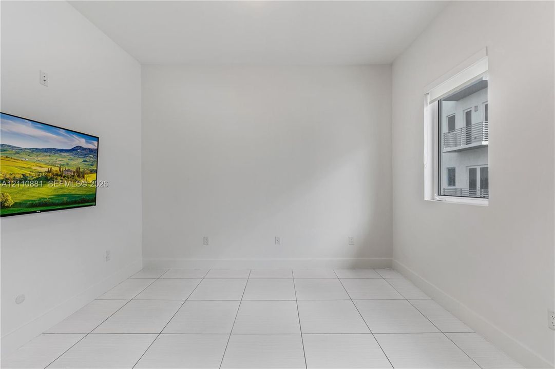 Bright interior space featuring large-format tile flooring, neutral wall finishes, and a single-pane window
