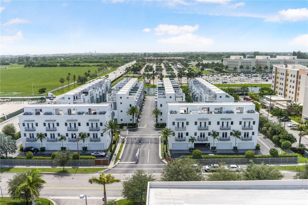 Gated community featuring multi-level townhome structures with private balconies, rooftop terraces, and integrated garage access