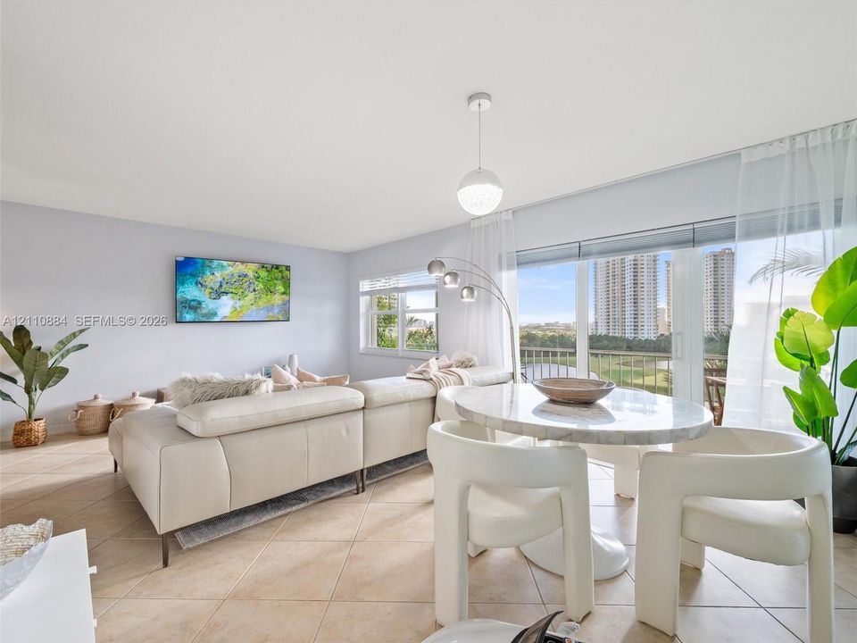 Open-concept living space featuring large-format diagonal tile flooring, floor-to-ceiling glass sliding doors, and a modern spherical pendant light fixture
