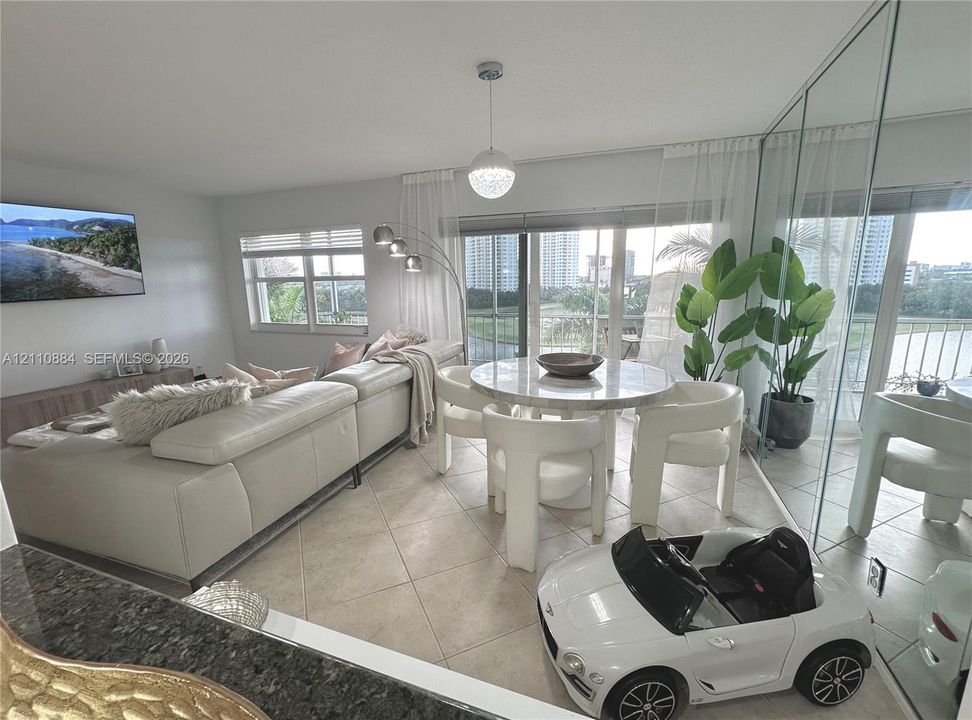 Open-concept interior featuring large-format ceramic tile flooring, floor-to-ceiling mirrored wall showcasing panoramic views with access to an exterior balcony