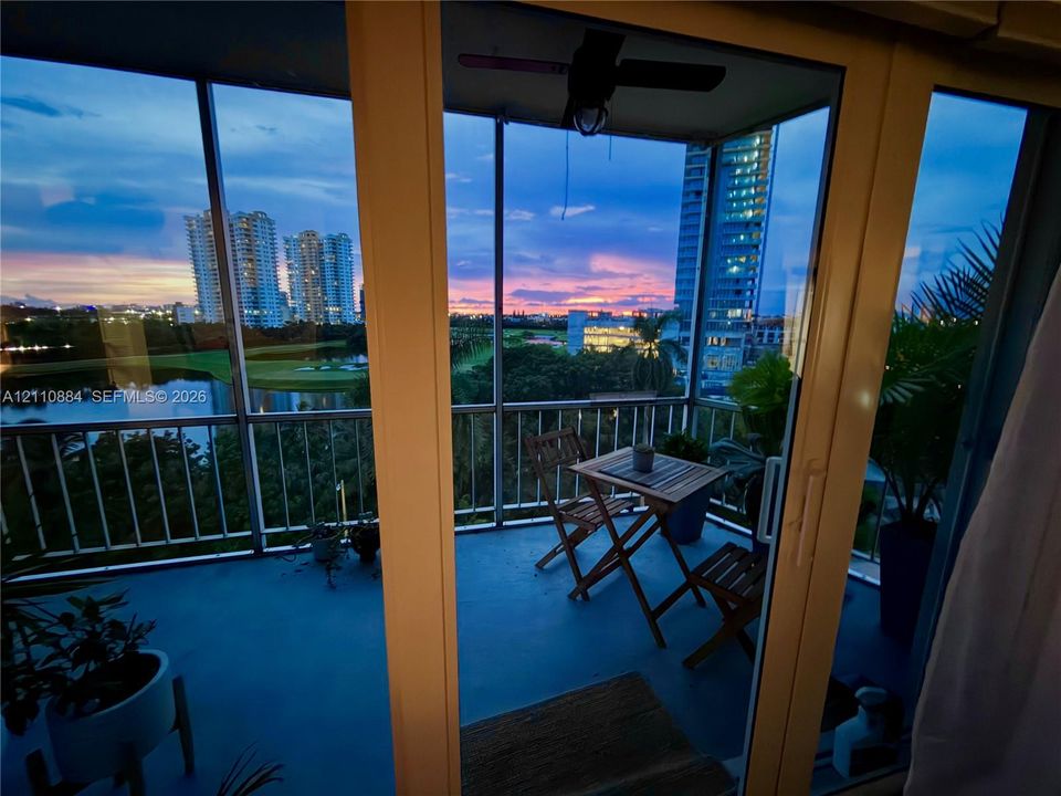 Screened-in balcony featuring sliding glass door access, metal railings, and overhead ceiling fan