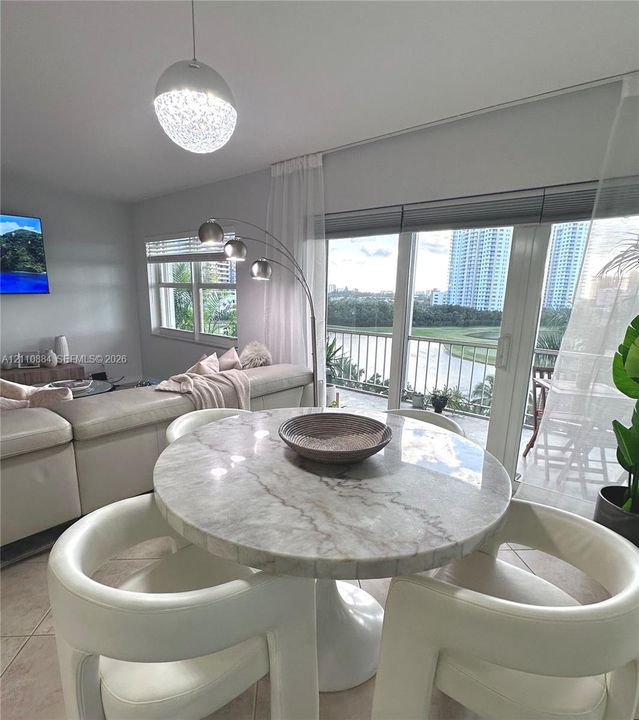 Open-concept interior featuring oversized tile flooring, recessed window treatments, a spherical pendant light fixture, and brand new impact rated floor-to-ceiling glass sliding doors opening to an exterior balcony