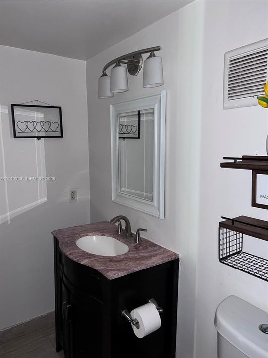 Dark-finish vanity featuring an integrated basin, stone-composite countertop, brushed-nickel faucet, and a three-light wall fixture