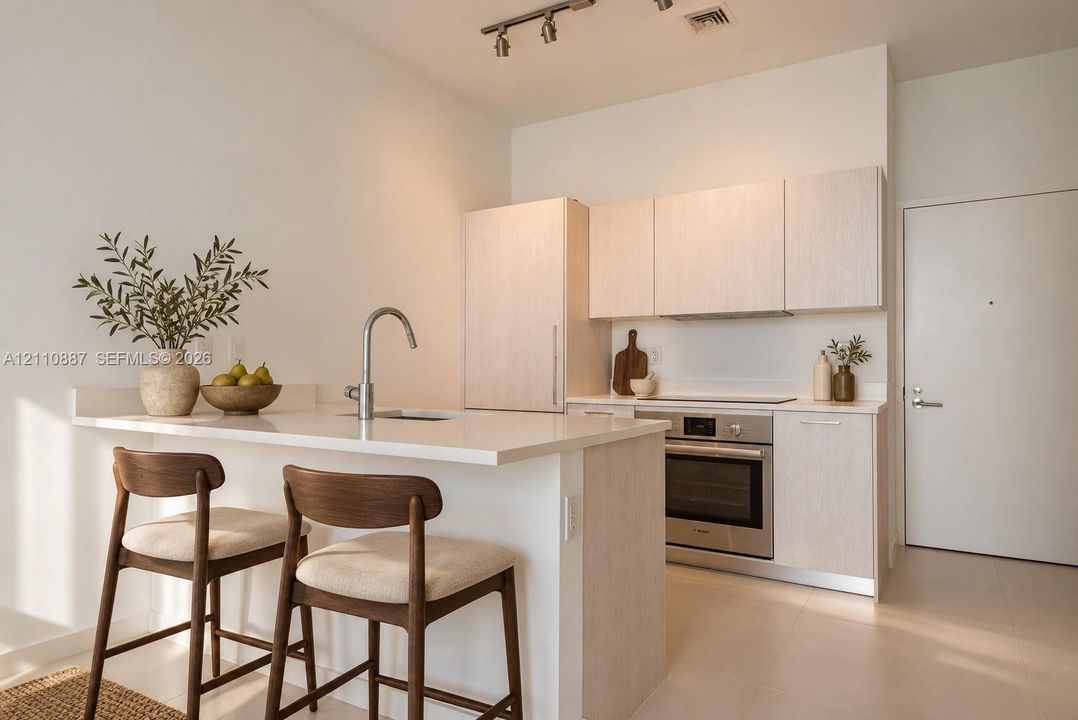 Kitchen featuring light-toned cabinetry, solid surface countertops, stainless steel oven, integrated refrigerator panel, and track lighting