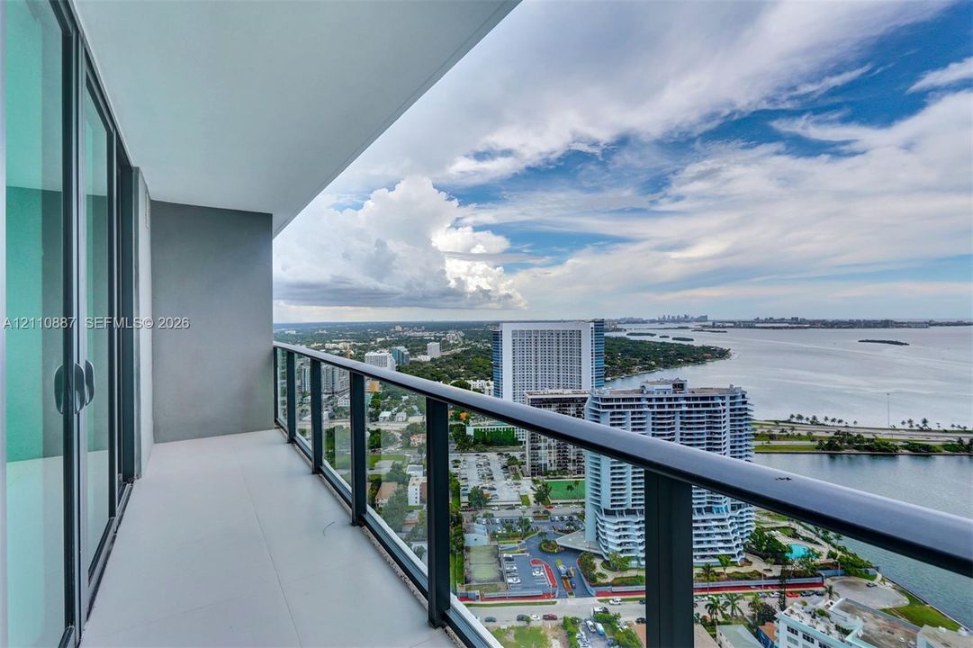 Covered balcony with a glass-panel railing and large-format tile flooring