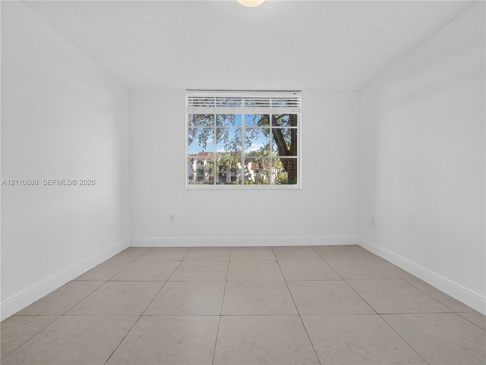 Neutral interior featuring large-format ceramic tile flooring, bright white walls, and a multi-pane window with integrated horizontal blinds