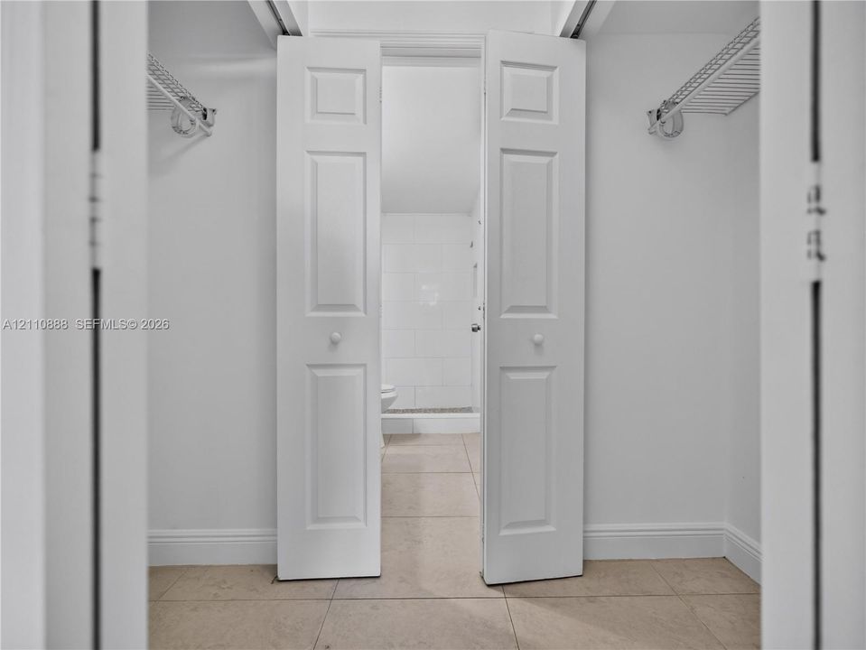 Walk-in closet featuring white paneled bi-fold doors, white interior walls, and built-in wire shelving