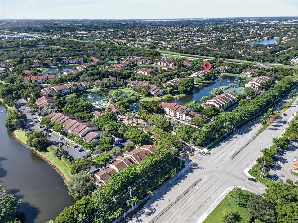 Aerial perspective of a multi-building residential community featuring tile roofs, mature landscaping, and interconnected lakes