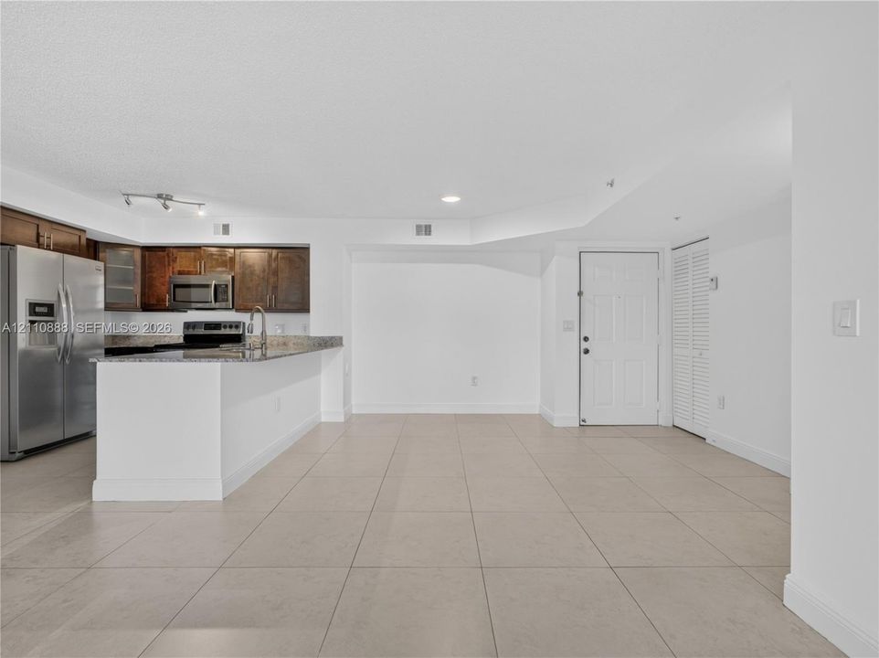 Kitchen featuring wood-finish cabinetry, stainless steel appliances, stone-surface countertops, and tile flooring