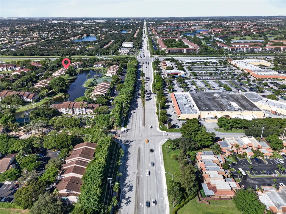 Aerial perspective showcasing multi-unit residential buildings with shingled roofing, established tree canopy, and a central water feature
