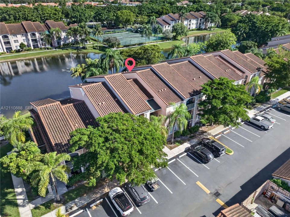 Multi-story residential building featuring a tile roof, light-colored stucco exterior, and waterfront placement along a canal