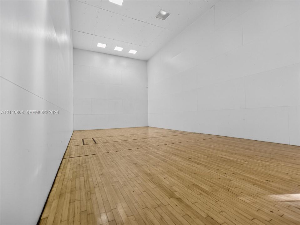 Athletic court featuring wood-finish flooring, smooth wall paneling, and recessed ceiling lighting