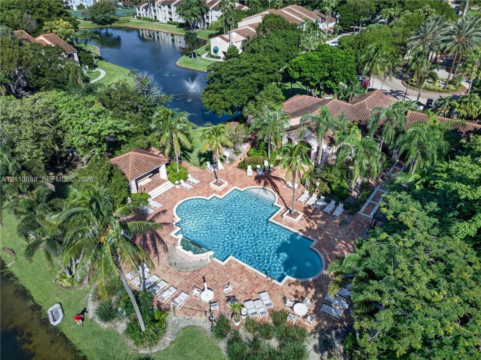 Aerial perspective featuring an expansive brick-paver pool deck, a swimming pool with tiered entry, and a covered pavilion structure