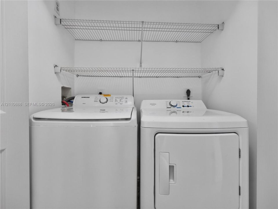 Laundry area featuring white top-load washer and front-load dryer with dual wall-mounted wire shelving units