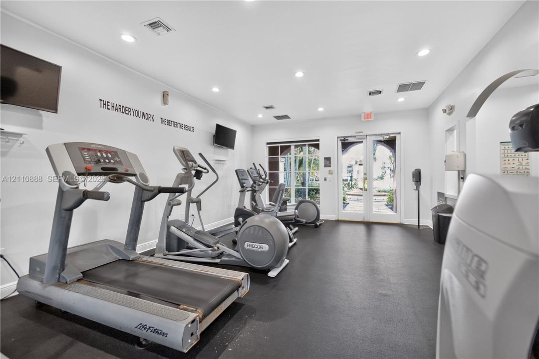Fitness center featuring resilient rubber flooring, recessed lighting, and double glass-paneled entry doors