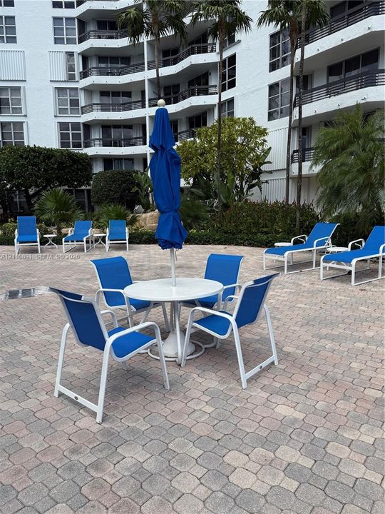 Paver patio featuring integrated landscaping, palm trees, and multi-story building exterior