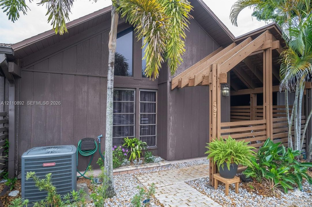 Vertical wood-paneled exterior, A-frame architectural detailing, oversized trapezoidal window, and timber-frame covered entryway with built-in latticework