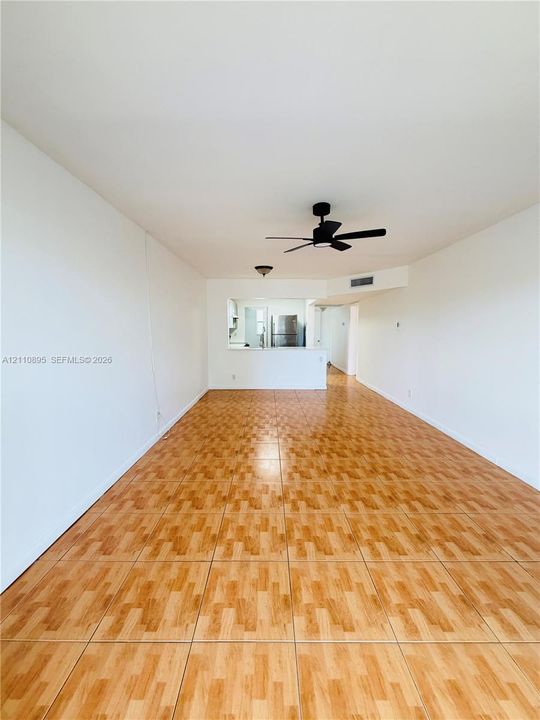 Interior space featuring wood-finish tile flooring, ceiling fan with integrated lighting, and a pass-through window with a built-in counter