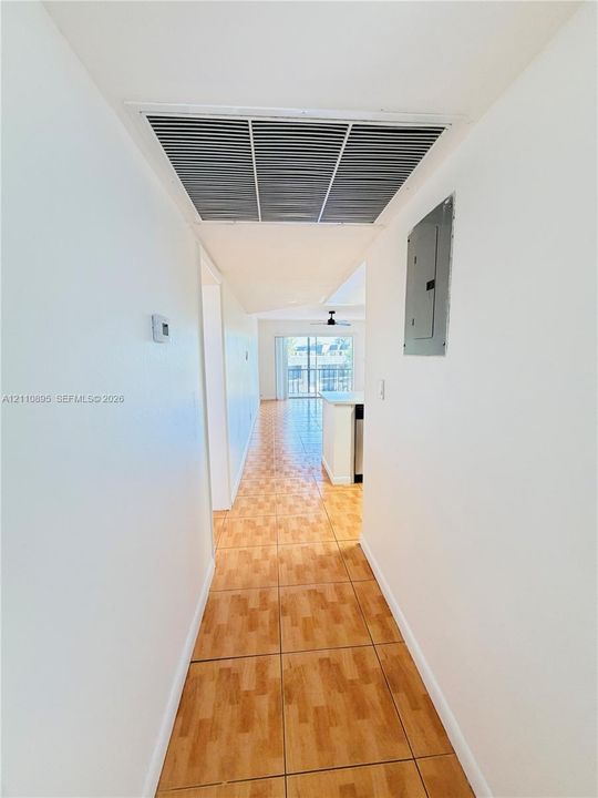 Tile flooring extending through the hall, recessed ceiling integration, and an electrical service panel