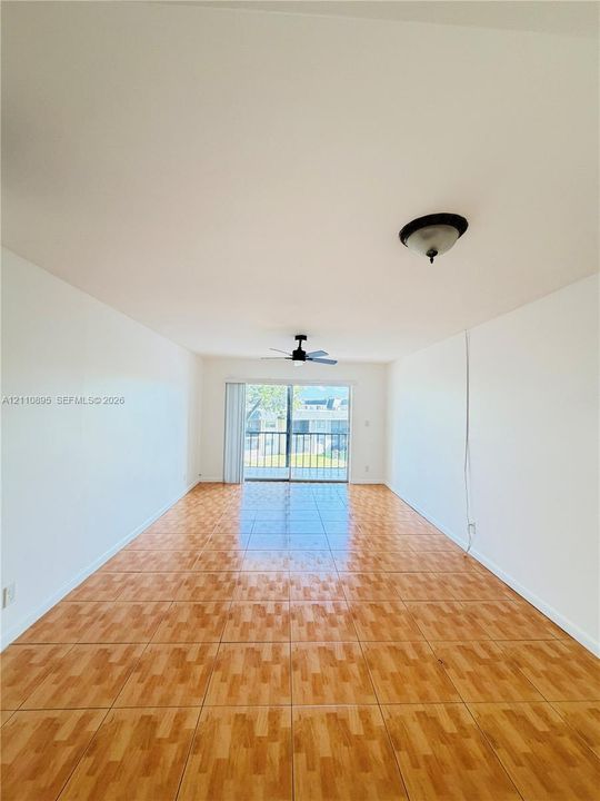 Interior space featuring tile flooring, ceiling fan with light fixture, flush-mount lighting, and sliding glass door with access to a balcony