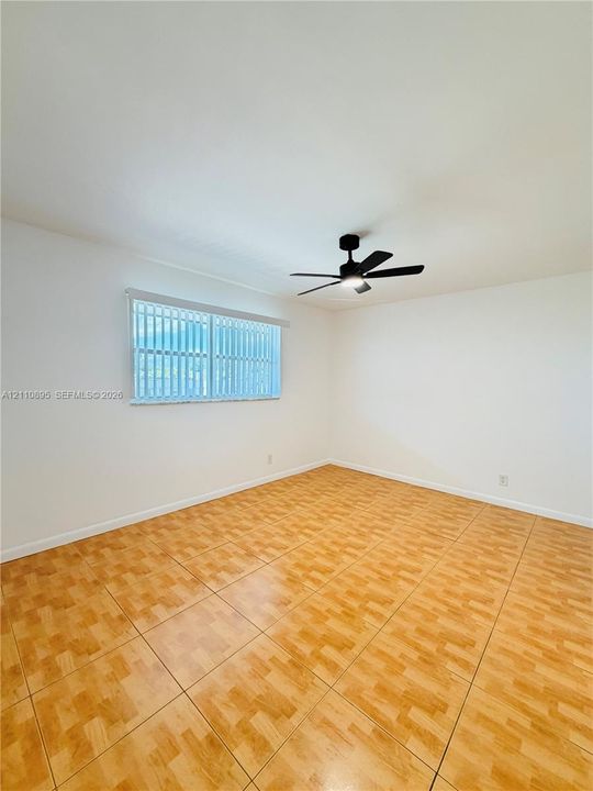 Neutral interior featuring tile flooring, a matte black ceiling fan, and a horizontal window with vertical blinds
