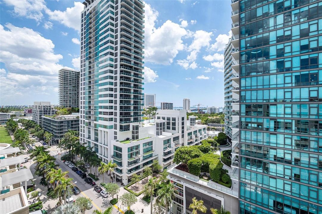 High-rise residential towers featuring floor-to-ceiling glass windows and private balconies, integrated with landscaped green rooftops and urban street-level palm tree lined pedestrian thoroughfares
