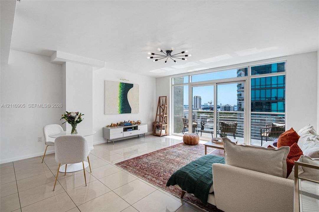 Polished tile flooring, modern sputnik-style ceiling lighting, and floor-to-ceiling glass sliding doors opening to a balcony