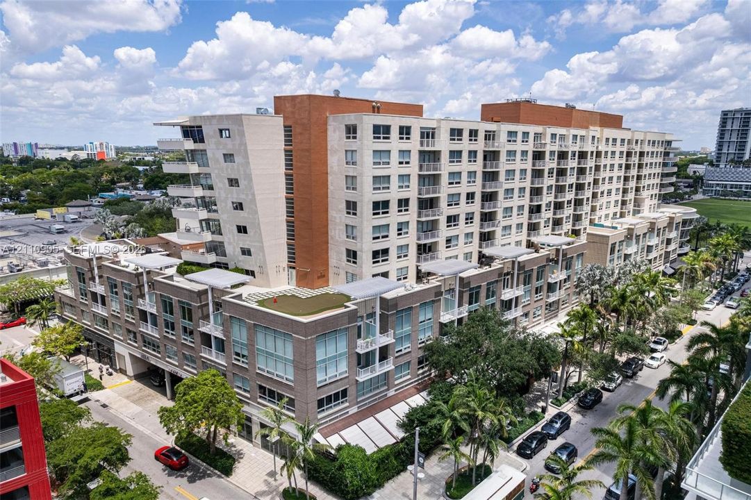 Mid-rise multi-story building featuring a brick and stone facade, expansive floor-to-ceiling windows, private balconies, and rooftop terraces