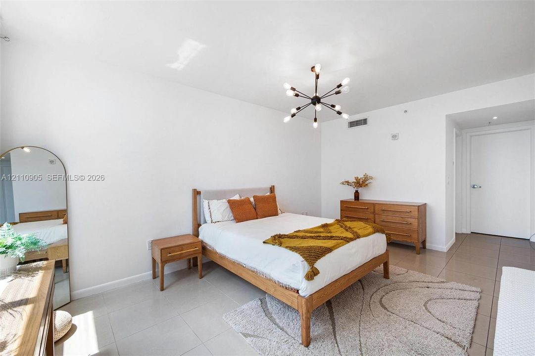 Spacious room featuring neutral tile flooring, smooth wall finishes, and a contemporary multi-arm sputnik-style light fixture