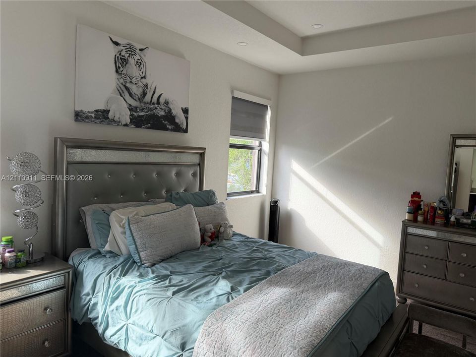 Tray ceiling with recessed lighting and a single window with roller shade