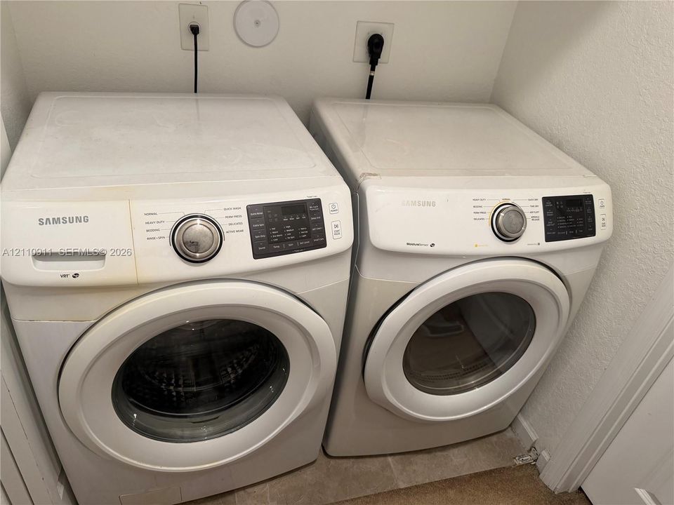 Side-by-side white front-loading washer and dryer set with digital control panels