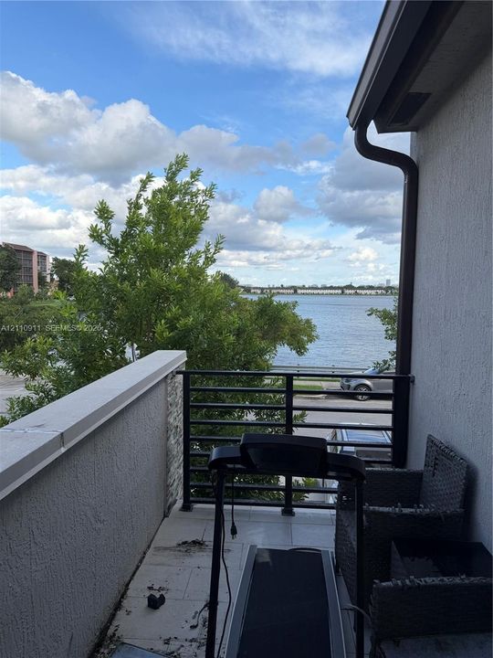Balcony featuring light-toned tile flooring, stucco wall finish, and a black metal railing