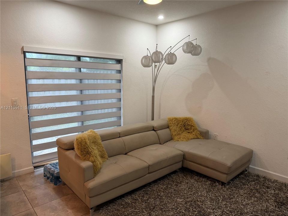 Sliding glass door featuring adjustable horizontal light-filtering shades and neutral tile flooring