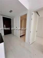Entry foyer featuring high-gloss tile flooring, solid dark-wood entry door, and recessed lighting