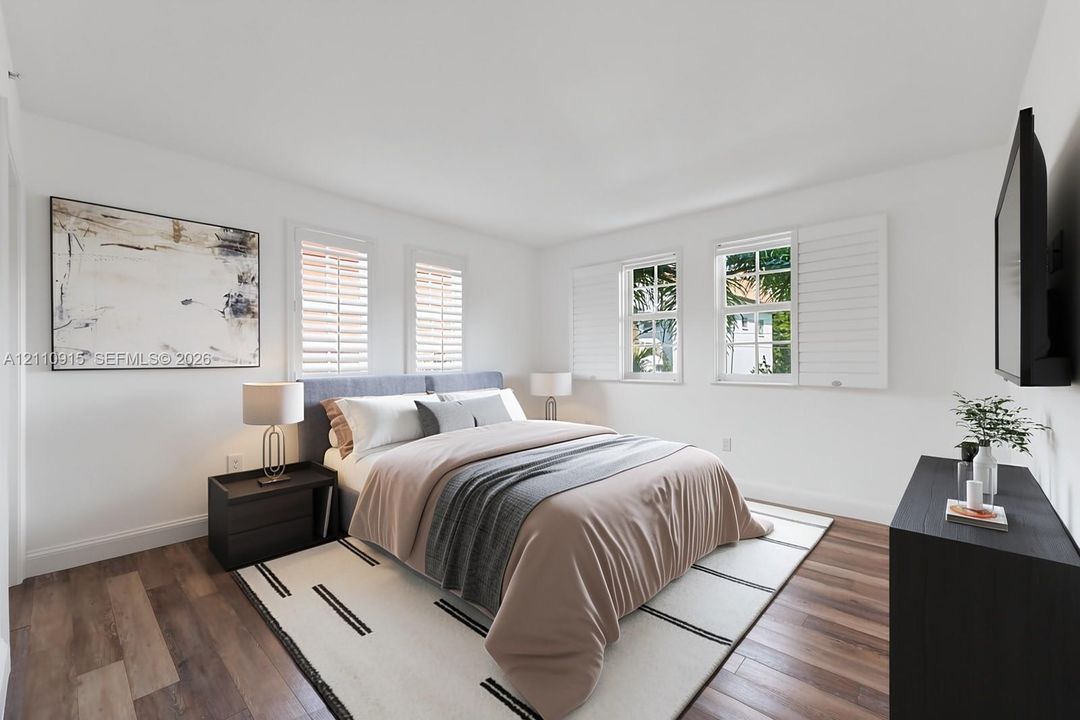 Bedroom featuring wood-finish flooring, white walls, and multi-pane windows equipped with adjustable plantation shutters