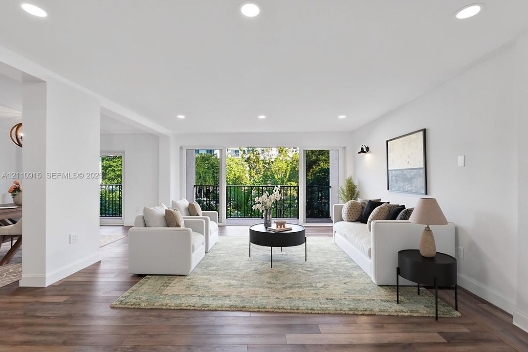 Open interior space featuring wood-finish flooring, recessed lighting, and large sliding glass doors leading to a balcony with metal railings