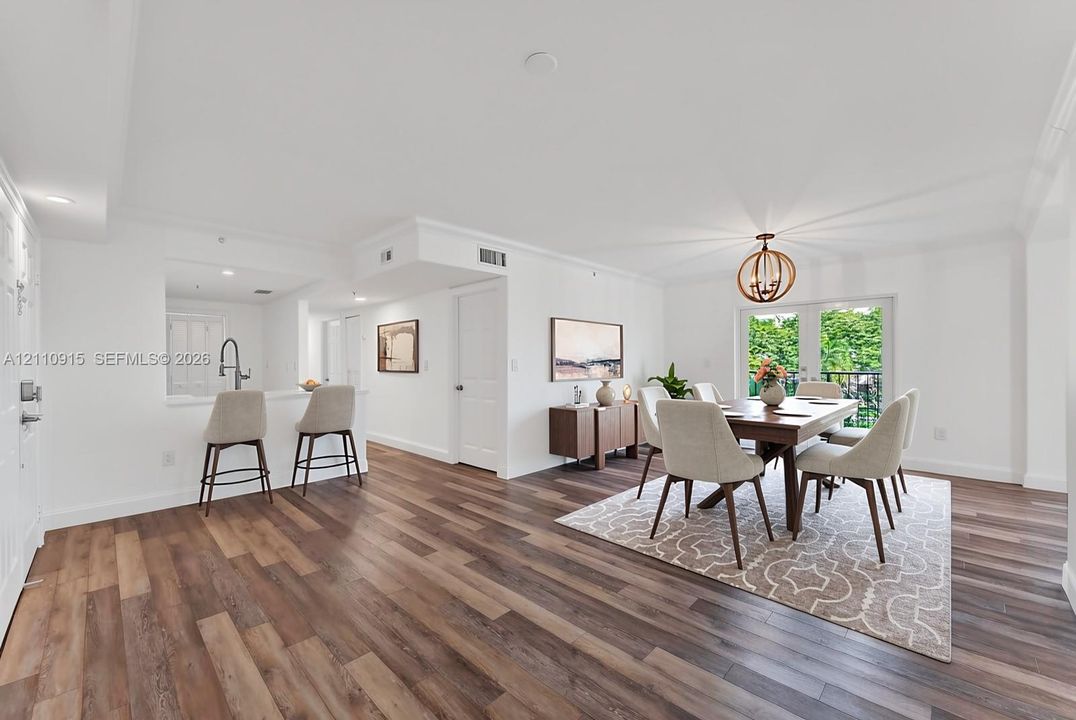 Open-concept area featuring wood-finish flooring, a kitchen pass-through counter with an attached faucet, and glass-paneled double doors